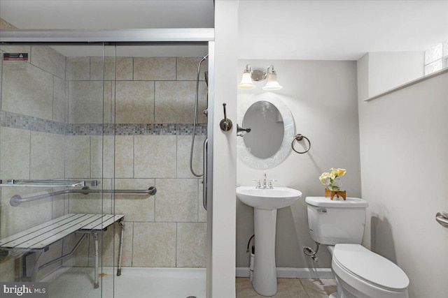 bathroom with tile patterned flooring, toilet, sink, and a tile shower