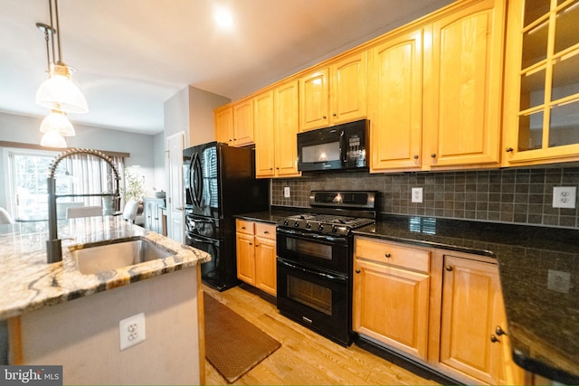 kitchen featuring pendant lighting, backsplash, dark stone counters, black appliances, and sink