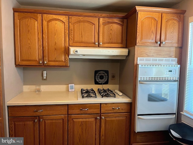 kitchen with white appliances, exhaust hood, light countertops, and brown cabinets