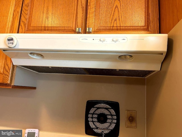 room details featuring under cabinet range hood and brown cabinets