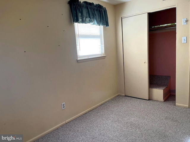 unfurnished bedroom featuring light carpet, baseboards, and a closet