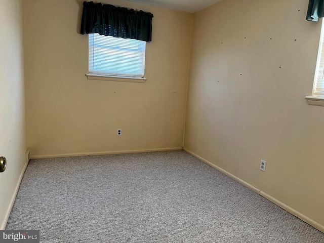 carpeted spare room featuring baseboards