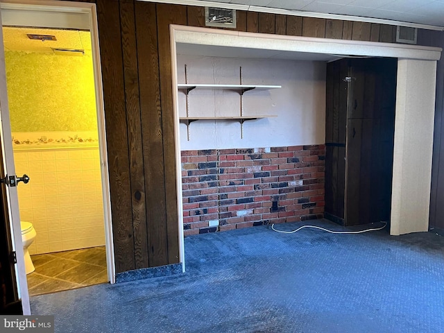 interior space with tile walls, wooden walls, and carpet