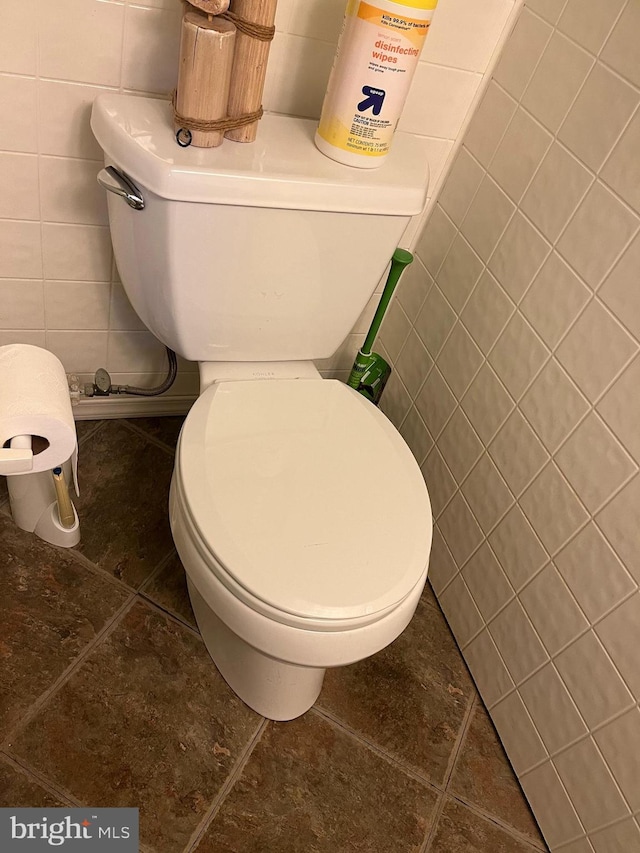 bathroom featuring toilet, tile walls, and tile patterned flooring