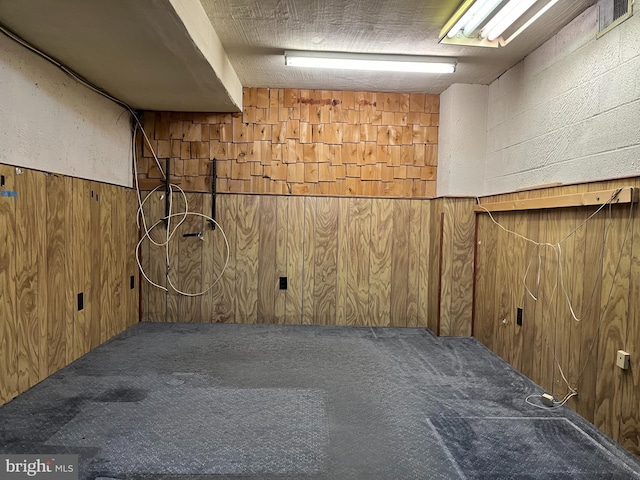 finished basement featuring carpet, visible vents, and wood walls