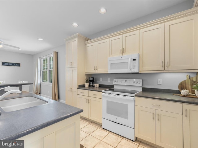 kitchen with white appliances, sink, light tile patterned floors, and cream cabinets