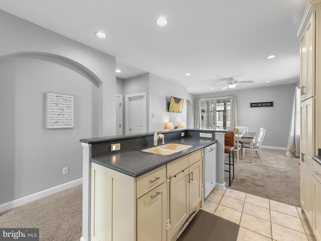 kitchen with light carpet, white dishwasher, ceiling fan, sink, and cream cabinetry