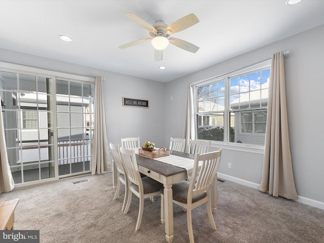 carpeted dining area with ceiling fan