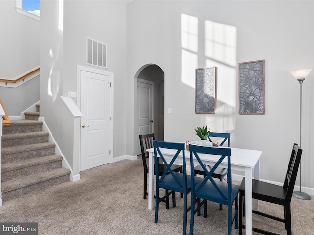 dining room with light colored carpet and a high ceiling