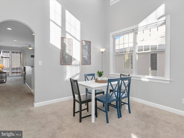 carpeted dining area featuring ceiling fan and a high ceiling