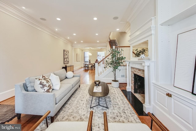 living room featuring a brick fireplace, light hardwood / wood-style flooring, and crown molding