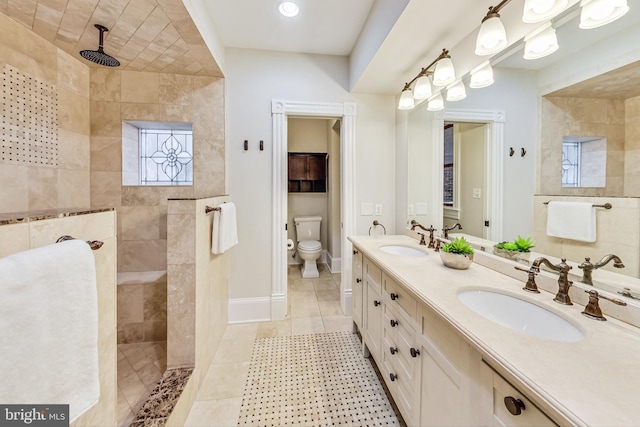 bathroom with vanity, toilet, tile patterned floors, and a tile shower