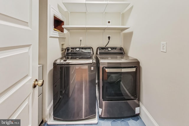 clothes washing area featuring washing machine and dryer and tile patterned floors