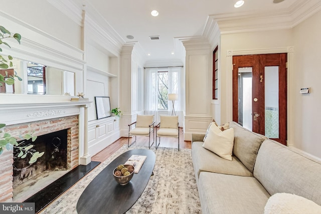 living room with crown molding, light hardwood / wood-style floors, and a brick fireplace