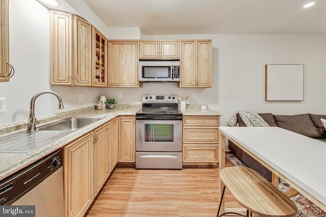 kitchen featuring sink, light brown cabinets, light wood-type flooring, and appliances with stainless steel finishes