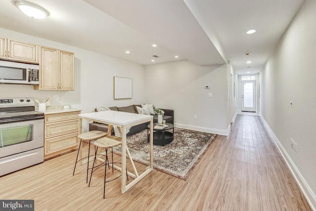 kitchen with light wood-type flooring, a breakfast bar area, and appliances with stainless steel finishes