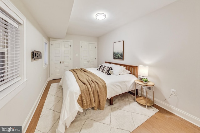 bedroom with multiple closets and light hardwood / wood-style floors