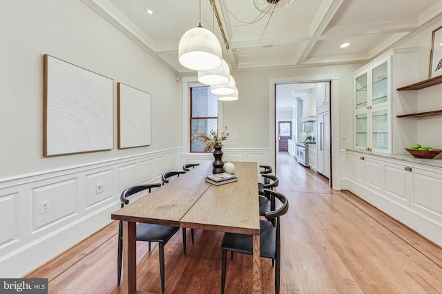 dining area featuring crown molding, coffered ceiling, light hardwood / wood-style flooring, and beamed ceiling