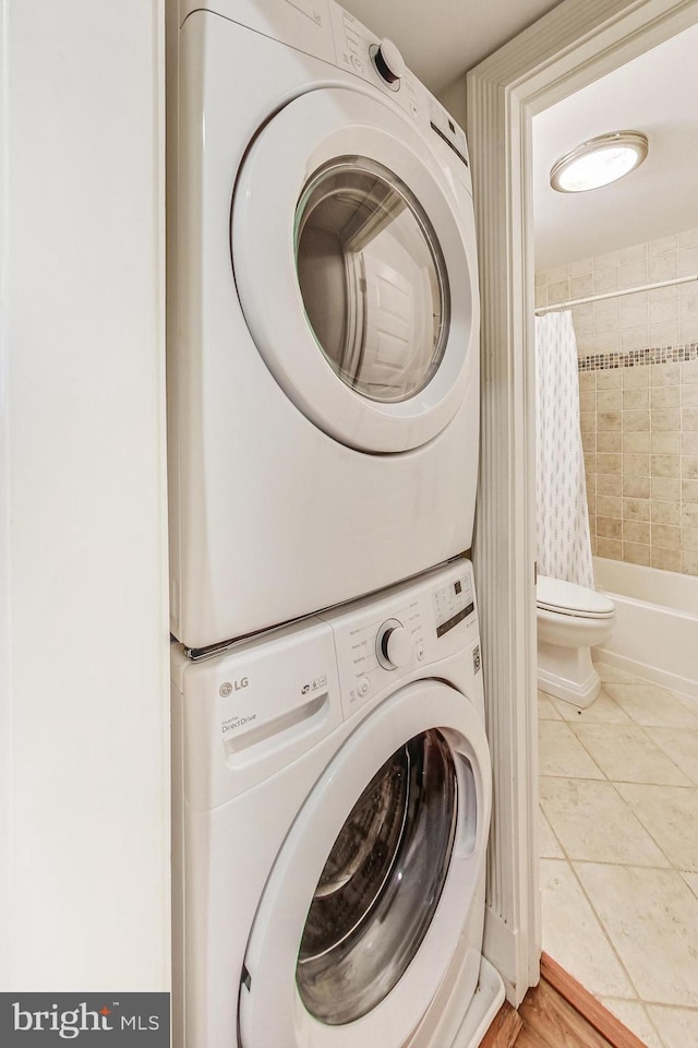 laundry area with stacked washer and clothes dryer and tile patterned flooring