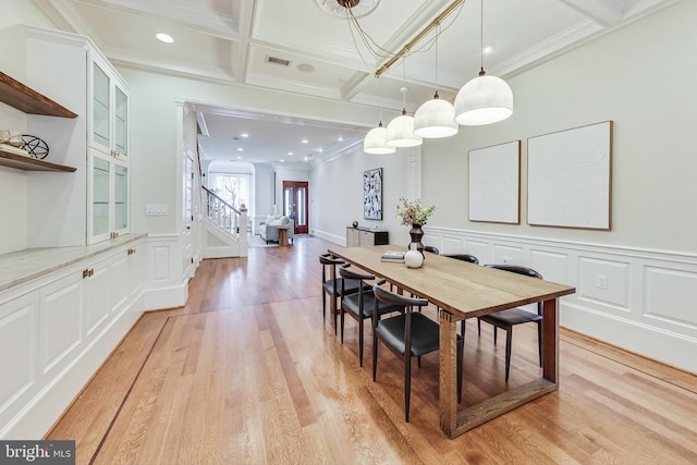 dining room featuring beam ceiling, coffered ceiling, light hardwood / wood-style flooring, and ornamental molding