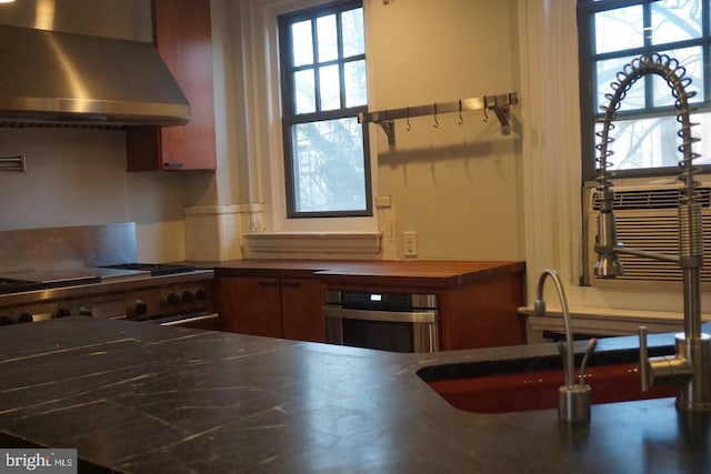 kitchen featuring sink, wall chimney range hood, and stainless steel appliances