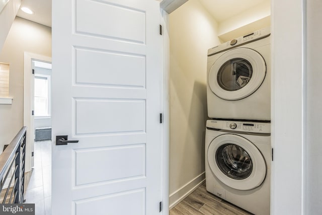 washroom featuring stacked washer and dryer and light hardwood / wood-style flooring