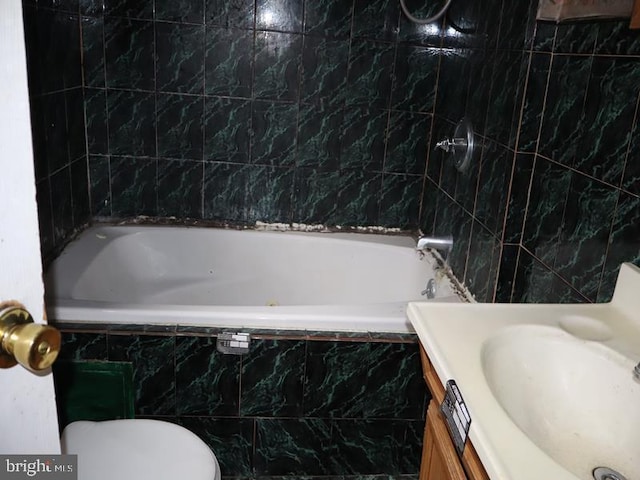 full bathroom with vanity, tiled shower / bath combo, tile walls, and toilet