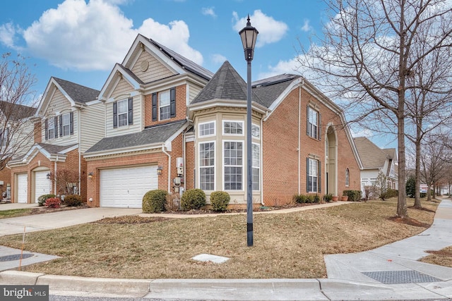 view of front of house with a garage, a front yard, concrete driveway, and brick siding