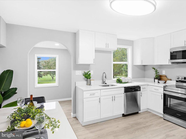 kitchen featuring white cabinets, light wood-type flooring, stainless steel appliances, and sink