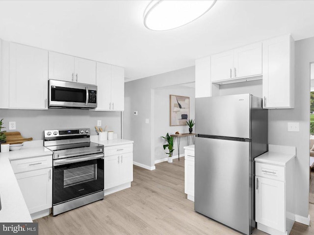 kitchen with white cabinets, stainless steel appliances, and light hardwood / wood-style flooring