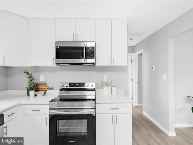 kitchen with appliances with stainless steel finishes, light wood-type flooring, and white cabinetry