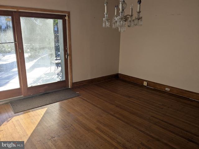 unfurnished dining area with dark hardwood / wood-style floors and a chandelier