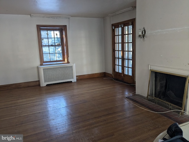 unfurnished living room with a tile fireplace, french doors, dark hardwood / wood-style flooring, and radiator