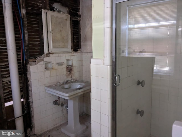 bathroom featuring a shower with shower door and tile walls