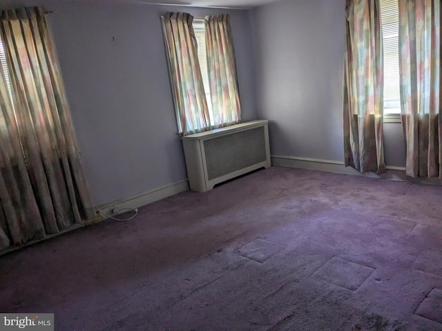 spare room featuring light carpet, radiator heating unit, and plenty of natural light