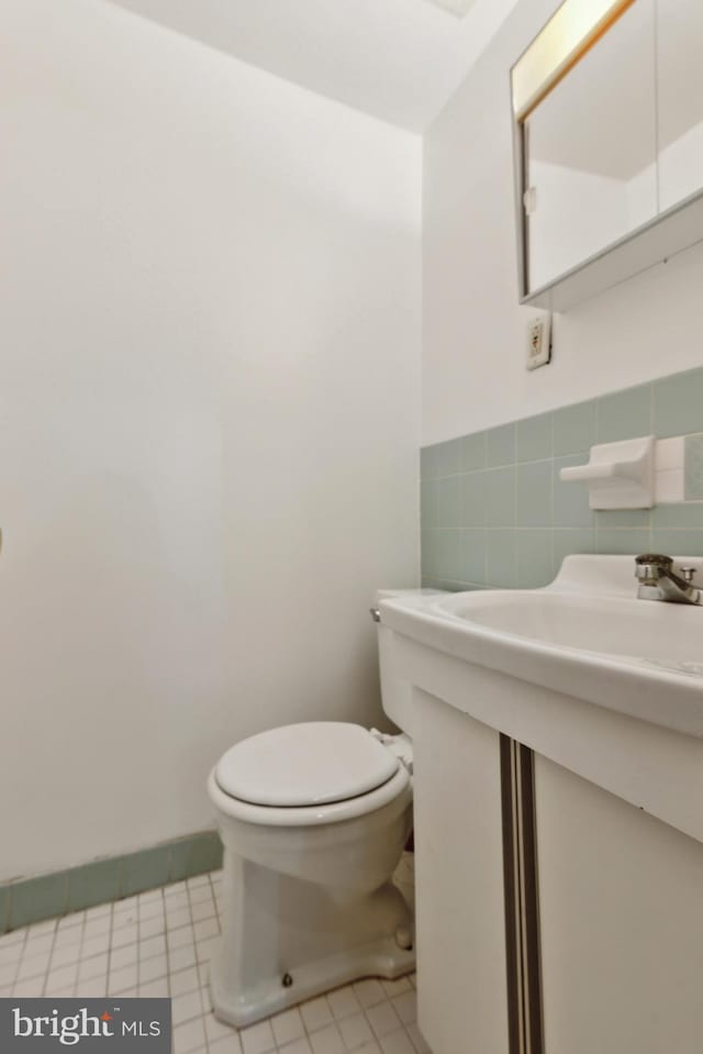 bathroom featuring tile patterned floors, toilet, and tile walls