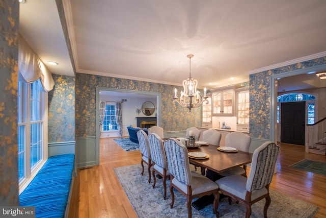 dining space with ornamental molding, hardwood / wood-style floors, and a notable chandelier