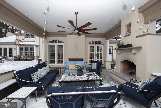 snow covered patio with an outdoor living space with a fireplace and ceiling fan