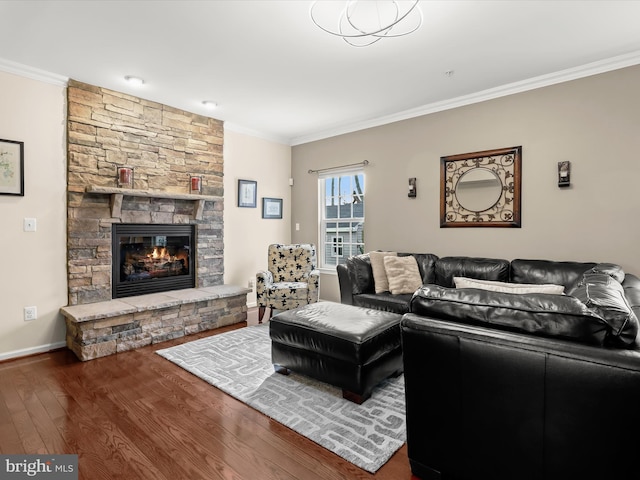 living area with baseboards, a stone fireplace, wood finished floors, and crown molding