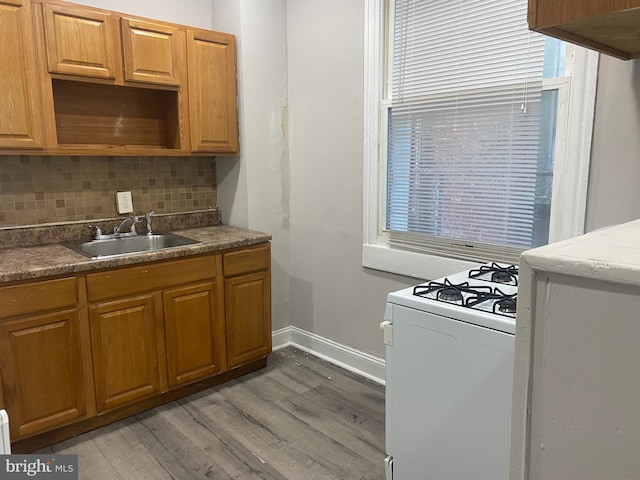 kitchen with tasteful backsplash, sink, white range with gas stovetop, and hardwood / wood-style flooring