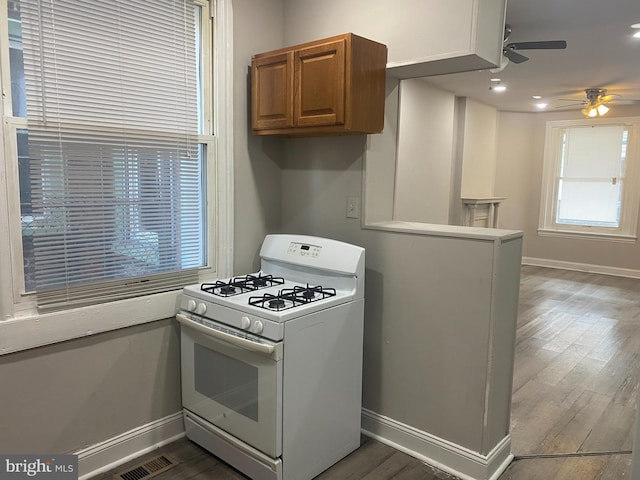 kitchen with hardwood / wood-style flooring, white gas stove, and ceiling fan