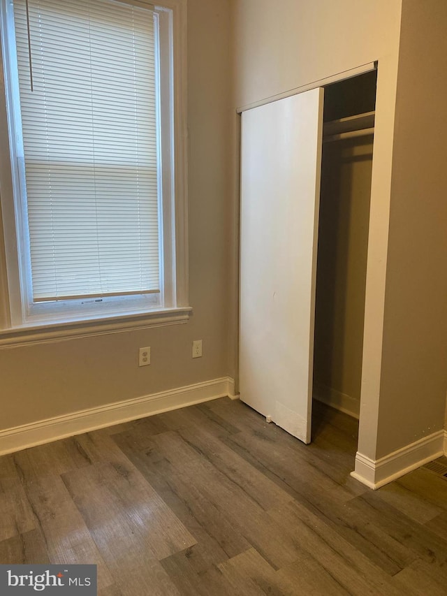 unfurnished bedroom featuring dark hardwood / wood-style flooring and a closet