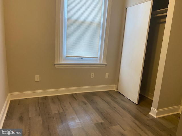 unfurnished bedroom with a closet and dark wood-type flooring