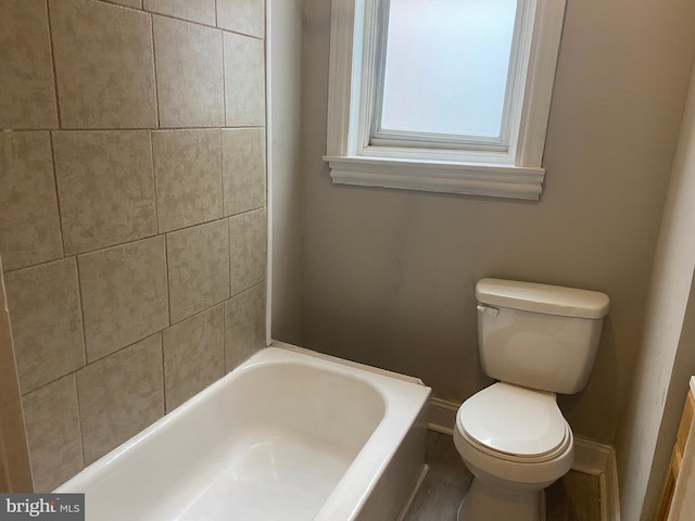 bathroom featuring toilet and a tub to relax in