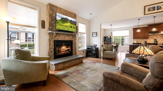 living room featuring dark hardwood / wood-style floors, a stone fireplace, and high vaulted ceiling