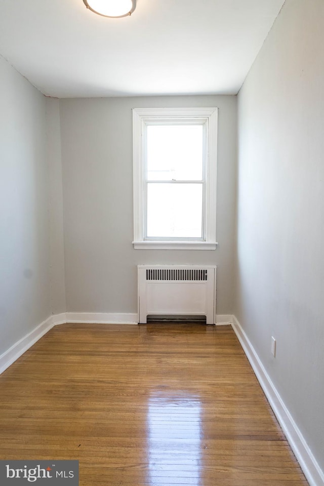 unfurnished room featuring light wood-type flooring and radiator heating unit