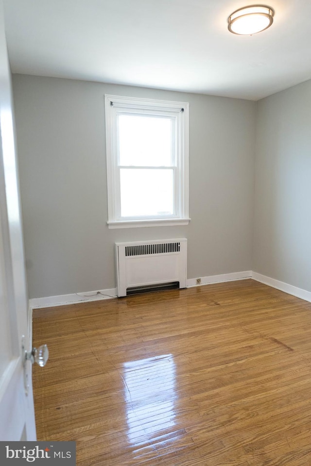 unfurnished room featuring radiator heating unit and light hardwood / wood-style flooring