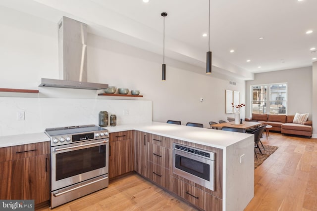 kitchen featuring tasteful backsplash, kitchen peninsula, wall chimney exhaust hood, and stainless steel range oven