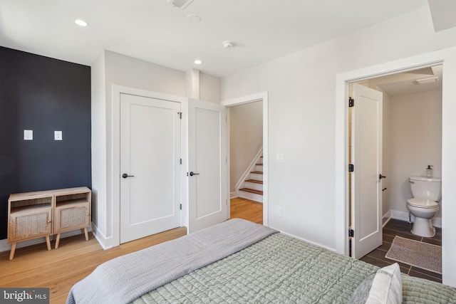 bedroom with ensuite bathroom and hardwood / wood-style floors