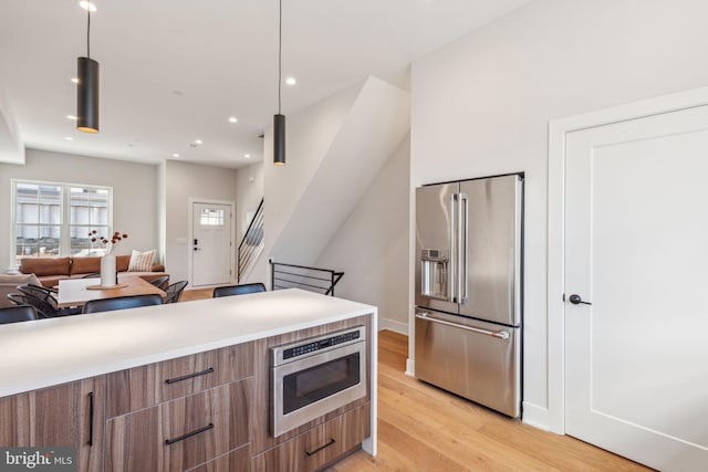 kitchen with decorative light fixtures, light wood-type flooring, and high end refrigerator